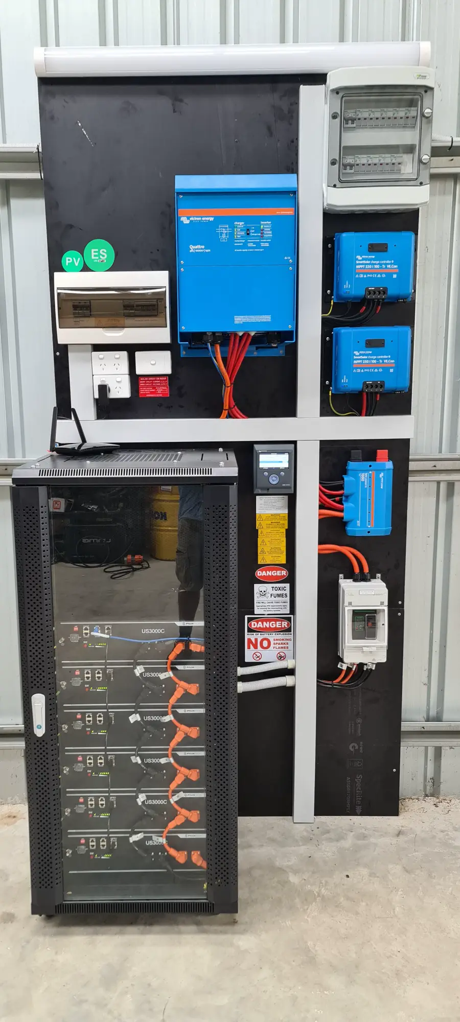 An off-grid battery cabinet with inverter and charge controllers mounted on a wall